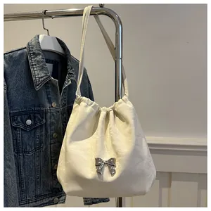 Detailed close-up of cream white PU leather bucket bag with silver metal bow and drawstring