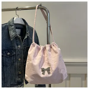 Detail of light pink bucket bag with pleated texture and silver metal bow ornament