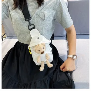Close-up of a white canvas chest bag featuring a 3D teddy bear and black shoulder strap