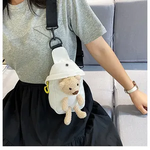Close-up of white canvas chest bag featuring a 3D plush bear and yellow carabiner detail