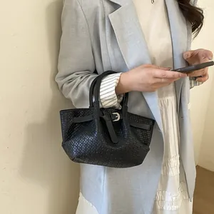 Elegant black woven leather bucket bag with silver buckle worn with a light blue blazer