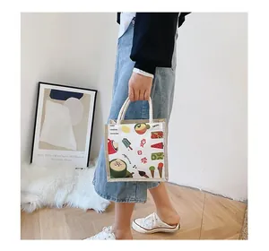 Close-up of beige canvas handbag featuring colorful summer icons and woven rope handle