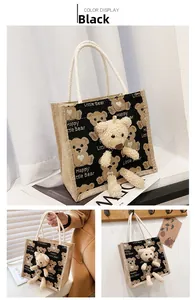 Close-up detail of a black canvas lunch bag with 3D plush bear and woven rope handles