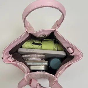 Pink woven bucket bag showing spacious interior with cosmetics and magnetic closure
