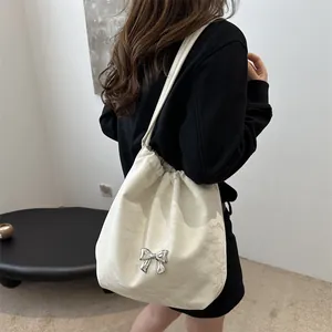 Minimalist white bow bucket bag with drawstring closure and silver metallic ribbon accent