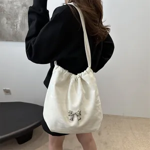 White textured leather bucket bag with silver metal bow and drawstring closure