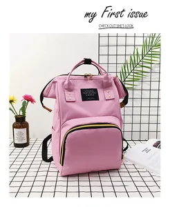 Close-up of pink canvas diaper bag with yellow zippers and woven travel label detail