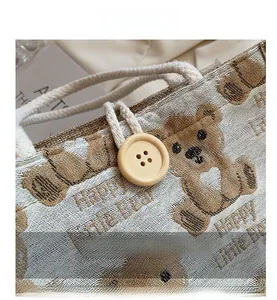 Detailed macro view of the wooden button closure and Happy Little Bear linen tote bag