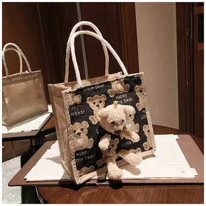 Detail of jute tote bag featuring 3D plush bear ornament and Happy Little Bear print