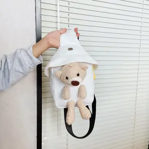 Dettaglio della borsa a tracolla in tela bianca con un simpatico orsetto di peluche