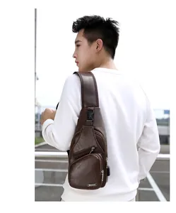 Détail du sac bandoulière en cuir marron foncé avec port USB et sangle sur un modèle homme