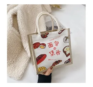 Detail of canvas tote bag with woven handles and bread illustration on a magazine background