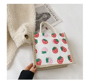 Detail of canvas strawberry tote bag featuring jute stitching and woven rope handles