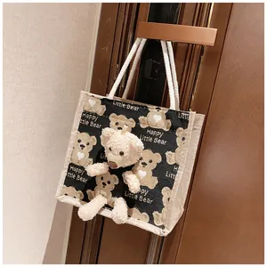 Detail of a black canvas bear tote bag with a plush bear toy hanging on a door