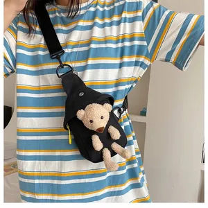 Detail of black canvas chest bag with a cute 3D plush bear and yellow zipper accent