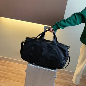 Waterproof nylon gym bag with dry-wet separation placed on top of silver luggage suitcase