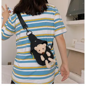 Detail of black canvas chest bag with cute plush bear and yellow zipper pull accent