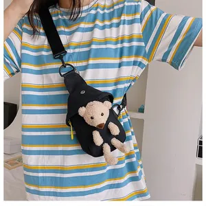 Detail of black canvas chest bag featuring a cute plush bear and adjustable strap