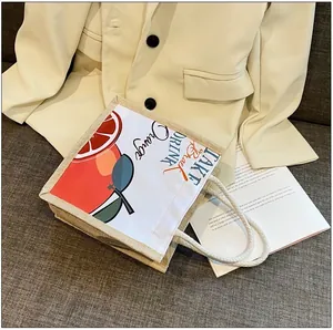 Close-up of linen tote bag with orange print and rope handles on a textured sofa