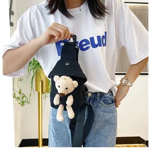 Close-up of black canvas chest bag featuring a cute 3D teddy bear plush decoration