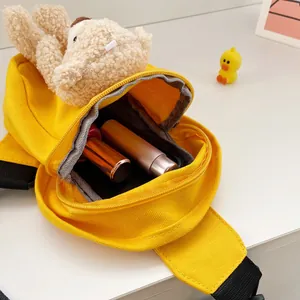Detalle del bolso de pecho de oso amarillo mostrando espacio para labial y móvil