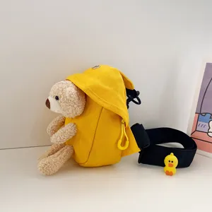 Dettaglio della borsa a tracolla in tela gialla con orsetto di peluche 3D e tracolla