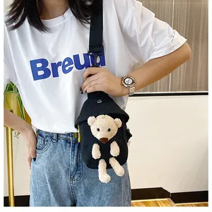 Close-up of black canvas chest bag with a cute beige plush bear and adjustable strap