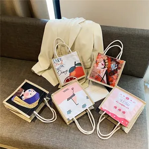 Five assorted mini linen tote bags with artistic cartoon prints on a soft grey sofa