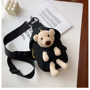 Detailed close-up of a black canvas chest bag featuring a plush 3D teddy bear charm