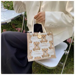 Detail of linen handbag featuring a cute bear print and rustic rope handles in garden