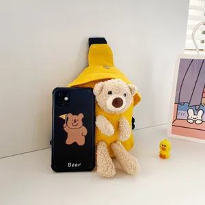 Dettaglio del borsello in tela gialla con orsetto di peluche beige e tracolla nera
