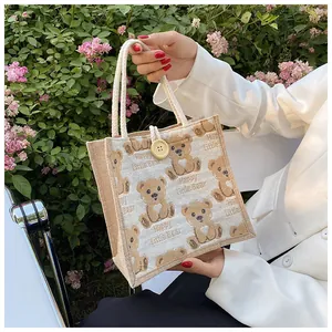 Detail of linen tote bag featuring cartoon bear print and a wooden button closure