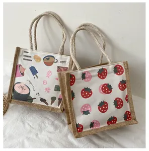 Detailopname van canvas draagtassen met aardbeien- en koffieprints en touwhandvatten