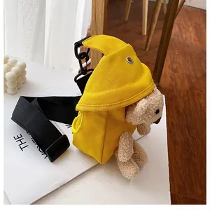 Detail of yellow canvas bag featuring a 3D plush bear ornament and adjustable black strap