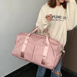 Pink nylon fitness bag with wet-dry separation shown worn as a crossbody travel duffel