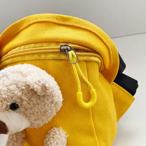 Dettaglio della borsa a tracolla in tela gialla con orsetto di peluche e cerniera a U