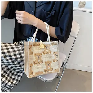 Detail of cute brown bear print and Happy Little Bear text on linen tote bag surface