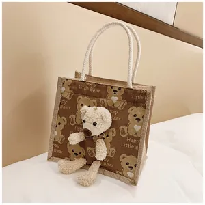 Close-up of brown canvas lunch bag with 3D plush bear and woven handles