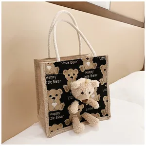 Close-up of linen tote bag with cartoon bear print and 3D plush bear detail