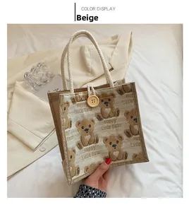 Close-up of beige linen tote bag with bear print, cotton rope handle, and wooden button