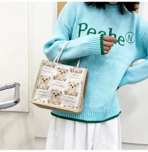 Detailed close-up of textured linen bear handbag with woven rope handles shown on model