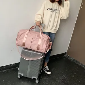 Pink waterproof nylon gym bag with luggage sleeve shown on a silver suitcase