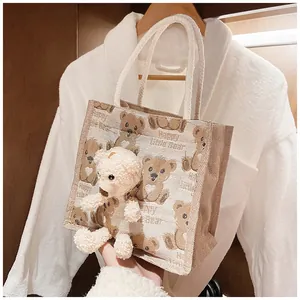 Detail of canvas lunch bag with cartoon bear print and a plush toy bear accessory