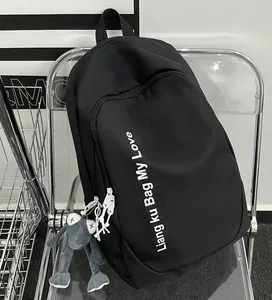 Detail of black letter backpack with plush doll charm on a modern transparent chair