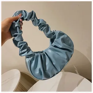 Detalle del bolso nube plisado azul claro con asa fruncida sostenido a mano