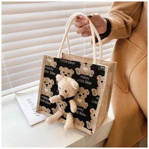 Detailed macro view of the 3D plush teddy bear and woven cotton rope handle on burlap bag