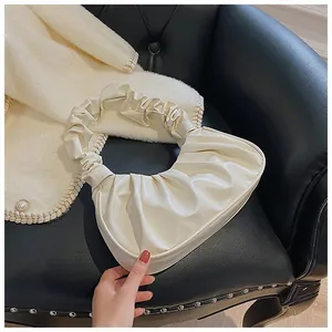 Detalle del bolso nube blanco mostrando el cuero sintético brillante y asa con pliegues