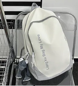 Close-up of white and grey contrast backpack with letter print and green frog plush pendant