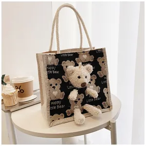 Close-up of beige linen tote bag featuring a 3D plush bear and woven rope handles