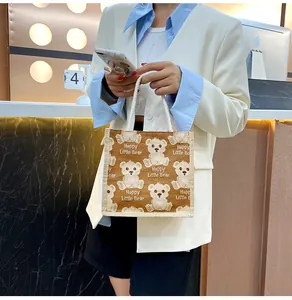 Detail of a brown linen bear tote bag with white woven handles shown by a model